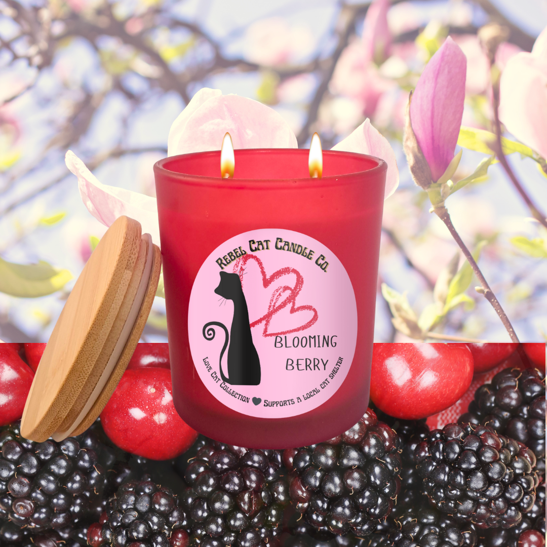 Red candle with a label featuring a cat silhouette and text, set against a natural background with berries and flowers.