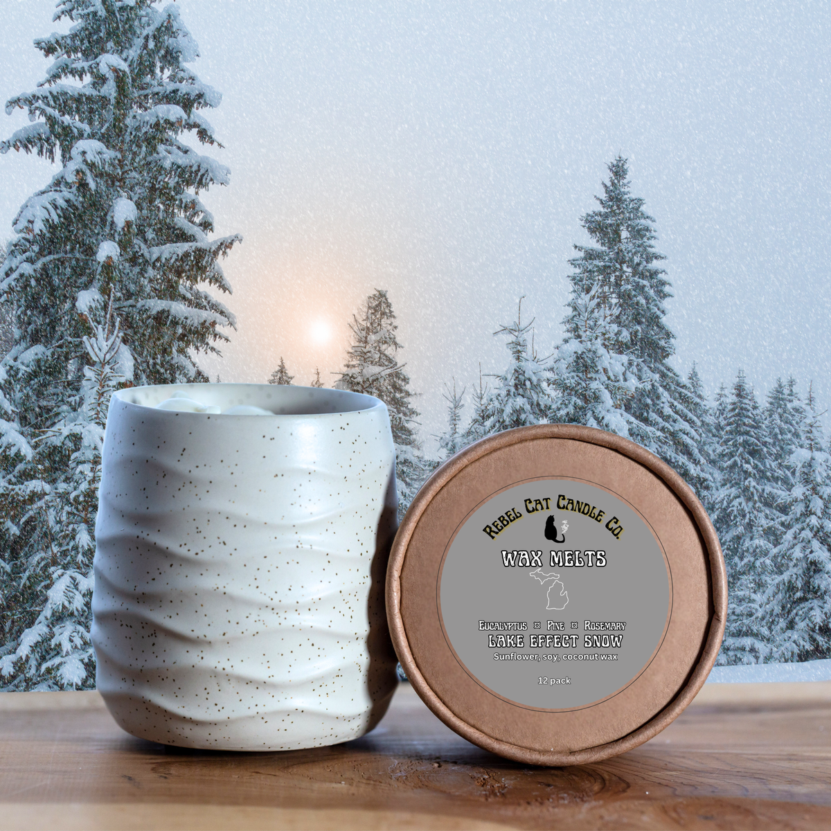 A ceramic wax melter with a wavy, ribbed texture in a warm off-white glaze sits next to its round kraft paper lid on a wooden surface. The lid features a gray label for 'Rebel Cat Candle Co.